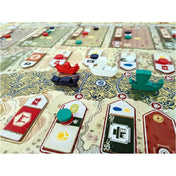 Közeli kép az Aranyfolyó társasjáték fa hajóiról és színes korongjairól a játéktáblán, a folyón és városrészek között mozogva.