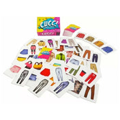 A Cucc! társasjáték doboza és tartozékai: színes ruhadarabokat ábrázoló kártyák szétterítve, háttérben a játék doboza élénk, vidám dizájnnal.