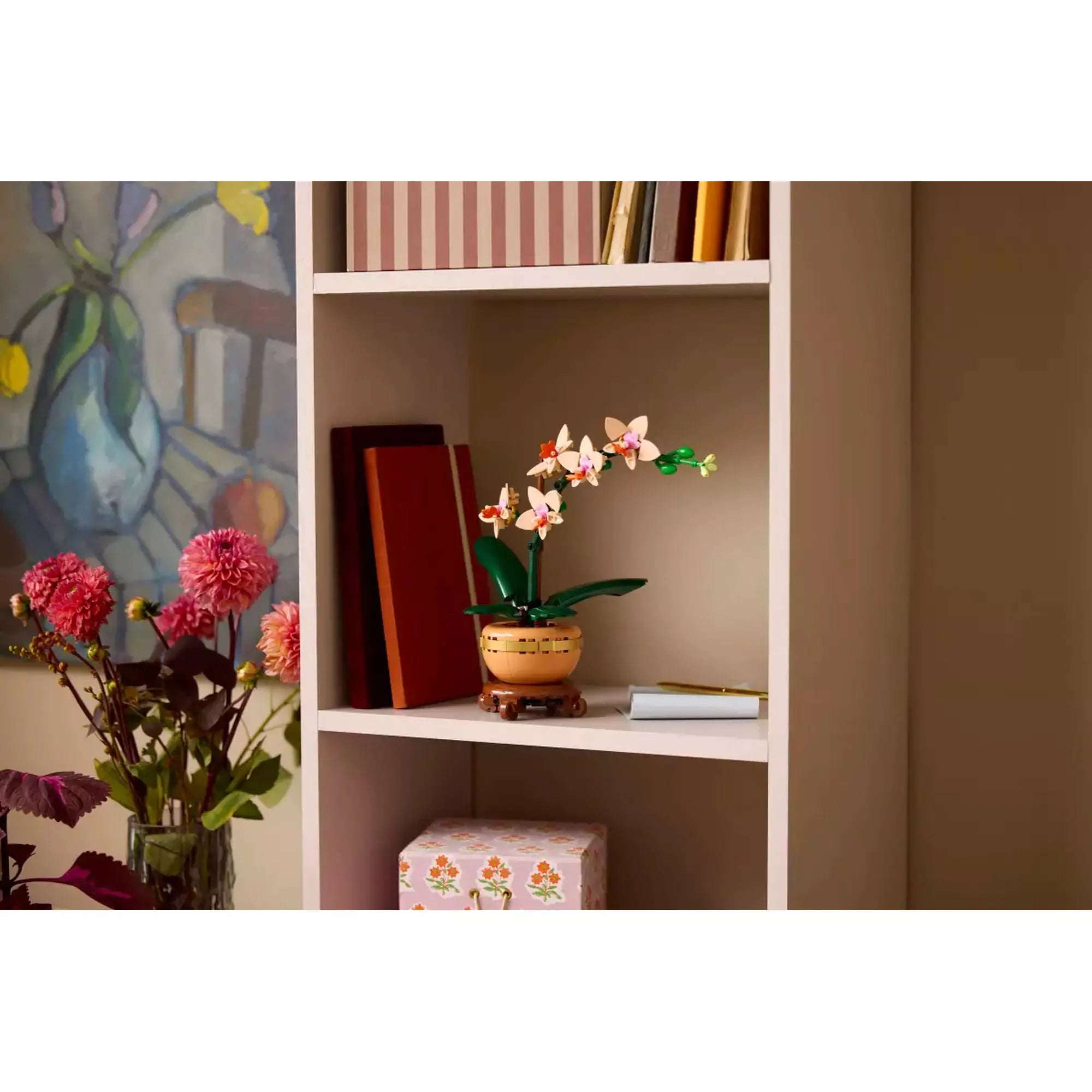 LEGO Mini Orchidea (10343) készlet elegánsan elhelyezve egy polcon, könyvek és dísztárgyak mellett, dekoratív elemként.