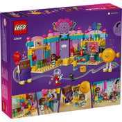 A LEGO Friends Heartlake City édességbolt 42649 szett hátsó nézete, amely bemutatja a színes édességbolt belső tereit, a nyalóka- és csokoládétábla kabalafigurákat, valamint a mini-baba figurákat és a bolt különféle játékelemeit, például a rágógumi-automatát, a cukorkás polcokat és az édességkészítő állomást.