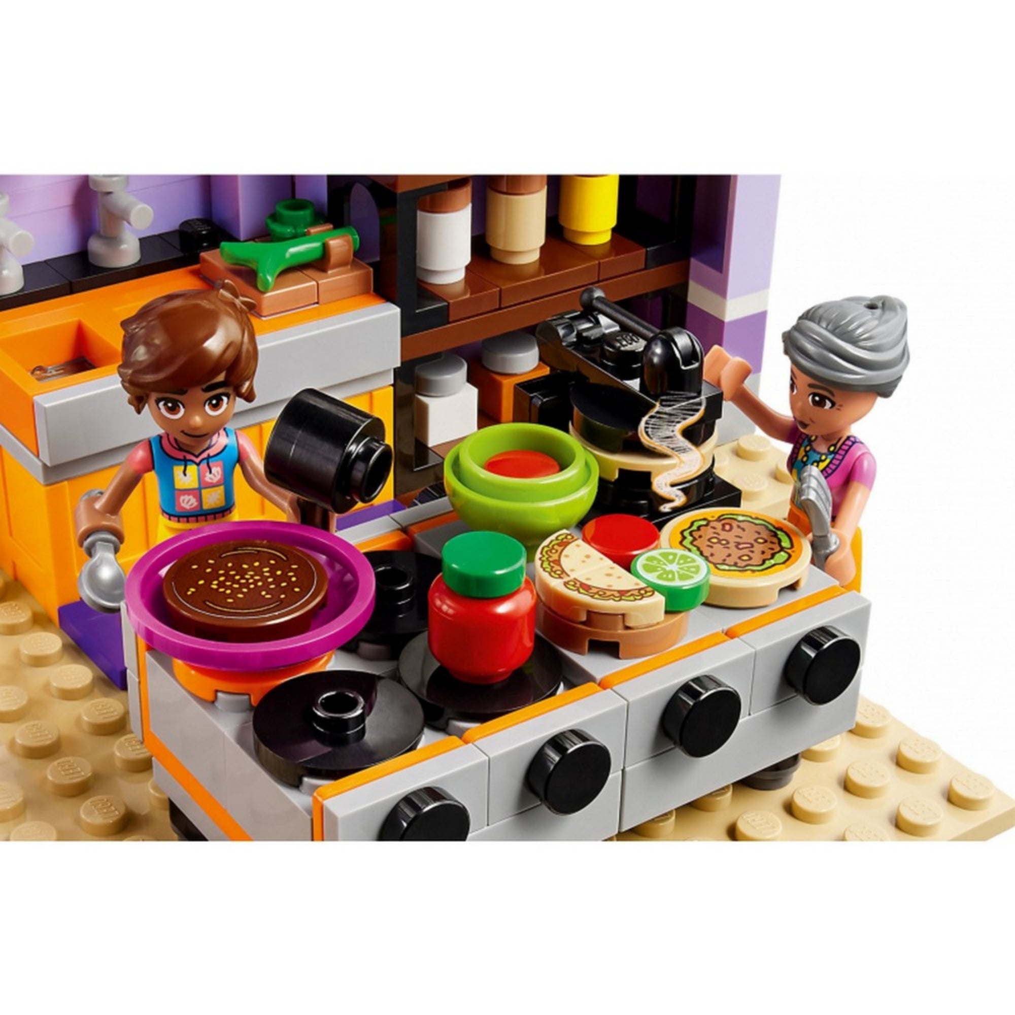 Részlet a LEGO Friends közösségi konyha belső teréből, ahol Leo és Abuelita ételeket készítenek: pizza, palacsinta és mártások sorakoznak a tűzhelyen.