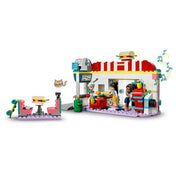 LEGO Friends 41728 Heartlake belvárosi büfé – a teljes épület elölnézetből: piros-fehér kupolás tető, „Diner” felirat, üvegajtók „OPEN” táblával. A három karakter (Aliya, Charli, Liann) különféle pozíciókban, gördeszkás jelenettel és cicával az étterem sarkánál.