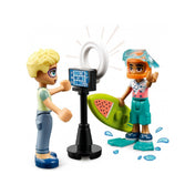LEGO Friends 41754 – jelenet, amelyben Olly épp videót rögzít Leóról, aki búvárszemüvegben, szörfdeszkával és uszonyokkal pózol. Egy LED gyűrűs fény és kamera is látható a fotózáshoz, miközben vízcseppeket imitáló LEGO elemek fokozzák az élményt.