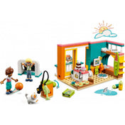 LEGO Friends 41754 Leo szobája – színes játékjelenet, ahol Leo és Olly karakterek egy napfényes, kreatív szobában játszanak. A jelenetben gördeszka, kamera, macskafigura, focikapuk és rengeteg kiegészítő szerepel, például sütis doboz, videó kamera és vízfestékfoltok a padlón.