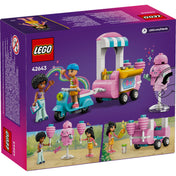 Ezen a képen a LEGO Friends Vattacukorárus stand és robogó 42643 szett hátoldala látható. A lila háttér előtt a szett tartalma látható: egy rózsaszín vattacukorárus stand, egy kék robogó és két LEGO Friends minifigura, Liann és Jamila, akik különféle szerepjátékos jeleneteket elevenítenek meg, például vattacukor árusítást és szórakozást egy parkos környezetben.