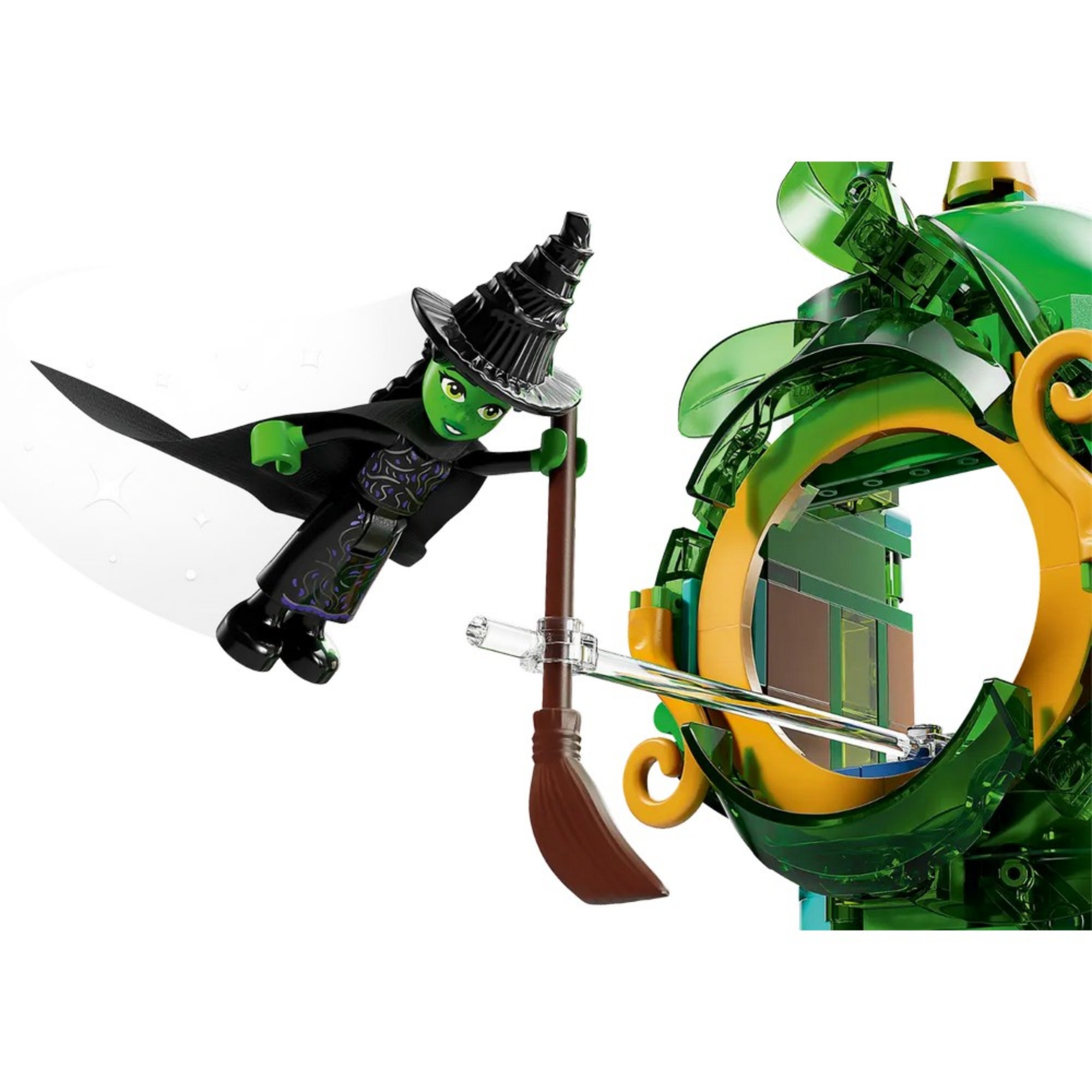 Közelkép a LEGO Wicked – Köszöntünk Emerald Cityben (75684) készlet boszorkány minifigurájáról, aki egy barna seprűn repül, áttetsző tartórúd segítségével a levegőben lebeg.