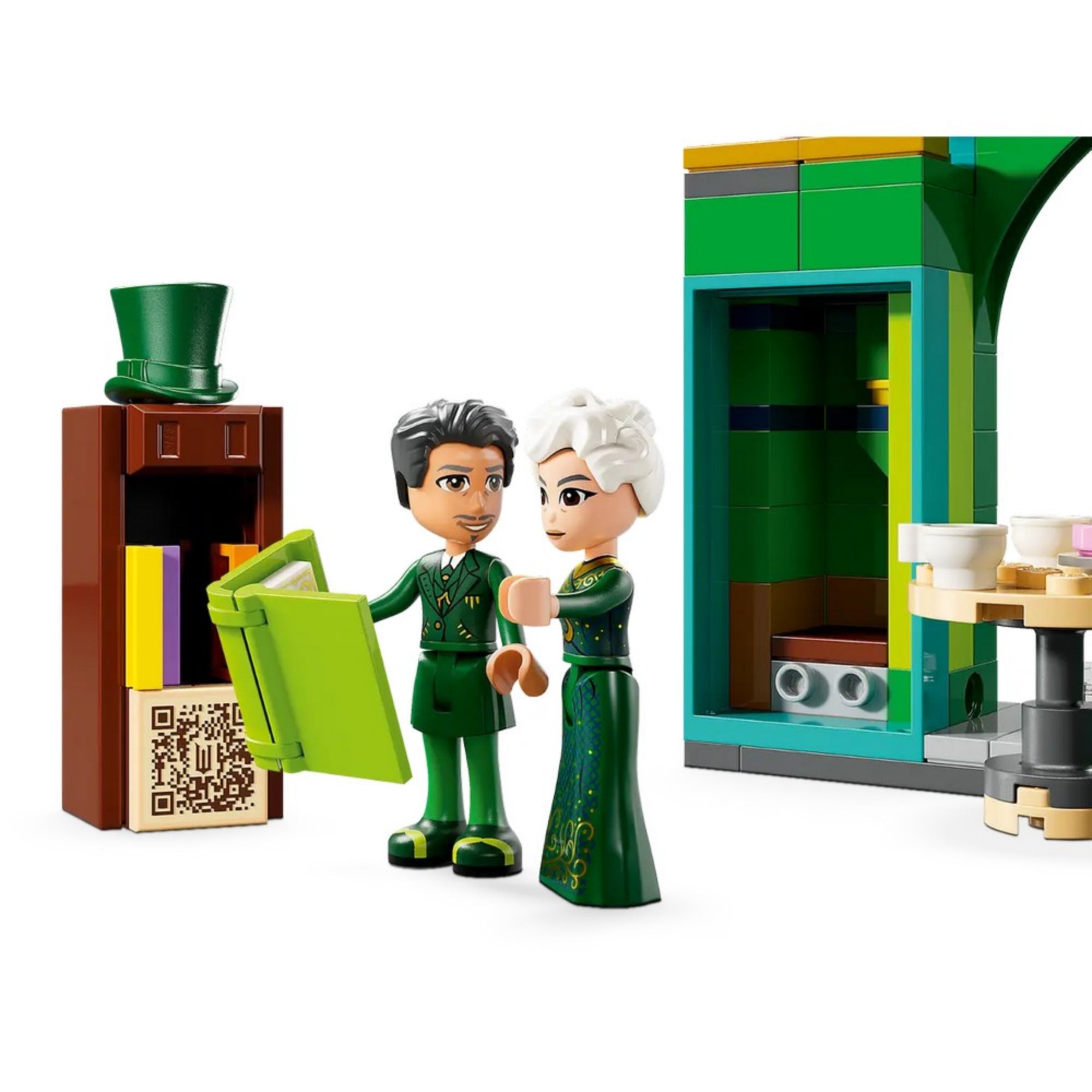 Közeli kép két karakterfiguráról a LEGO Wicked – Köszöntünk Emerald Cityben (75684) készletből, háttérben egy zöld LEGO épületrészlet, előtérben egy könyvespolc és egy zöld színű nyitott könyv.
