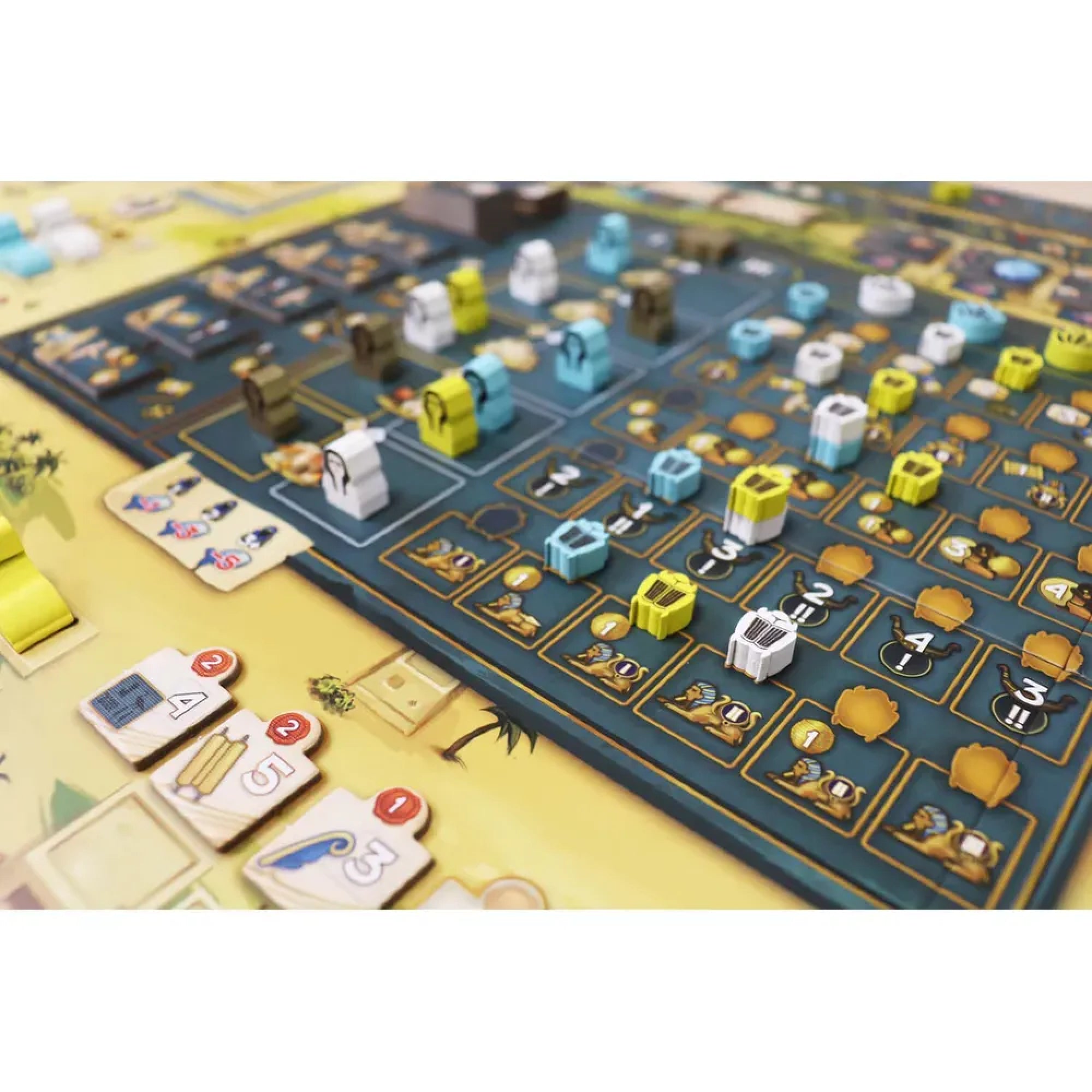 A Men Nefer társasjáték táblájának részlete, színes játékelemekkel, kincsesládákkal, szimbólumokkal és egyiptomi mintákkal, stratégiai elrendezésben.