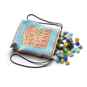 A képen a River Valley Glassworks társasjáték egyik fontos eleme, egy díszes húzózsák látható, amelyből különböző színű és formájú üveglapkák ömlenek ki. A zsák mozaikszerű mintázata illeszkedik a játék kézműves és esztétikus hangulatához. Az üveglapkák gyűjtése és felhasználása a játék egyik központi mechanikája, amely stratégiai döntéseket igényel a játékosoktól.