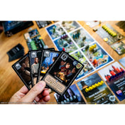 Játékos kézben tartott Tiny Epic Game of Thrones kártyák közelről, köztük Tyrion Lannister karakterkártyája, háttérben a játékmező.