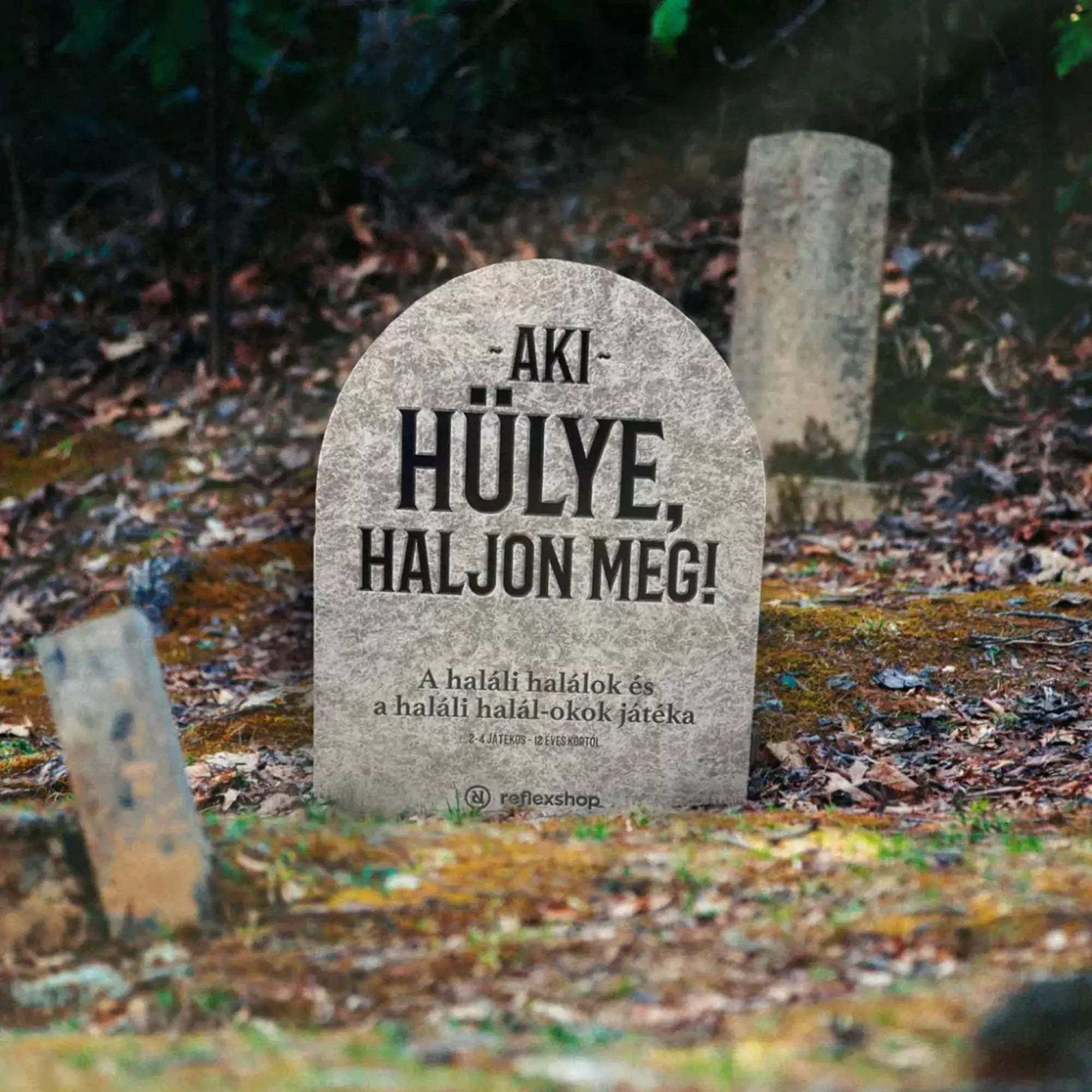 Az Aki hülye, haljon meg! társasjáték doboza temetői környezetbe helyezve, vicces haláltematikával.