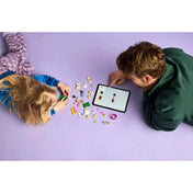 Egy kisgyermek és egy felnőtt együtt játszik a LEGO Friends Puppy Playground (42665) készlettel, miközben egy tablet segítségével nézik az összeszerelési útmutatót.