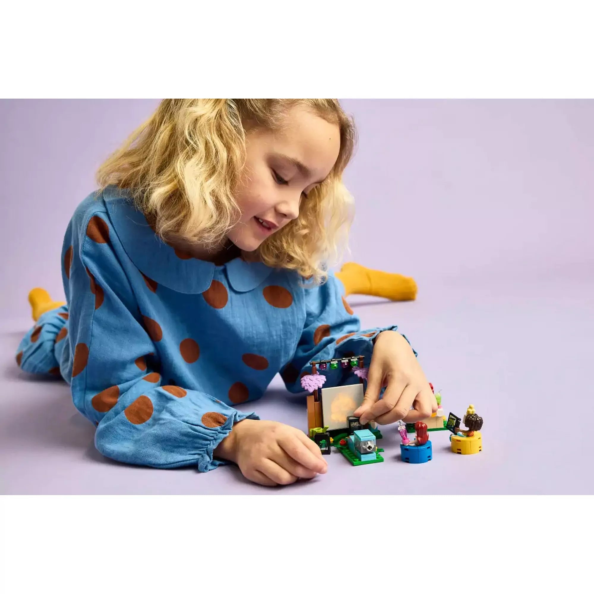LEGO Friends – Moziest a barátokkal (42642) játék közben gyermekkel – Egy szőke kislány játszik a Moziest a barátokkal LEGO készlettel, miközben elmerül a kültéri mozi jelenetben.