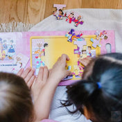 Gyerekek Melissa & Doug mágneses kirakó – Hercegnők darabjait illesztik össze a mágneses táblán, közelről látható a színes királyi bál jelenet.