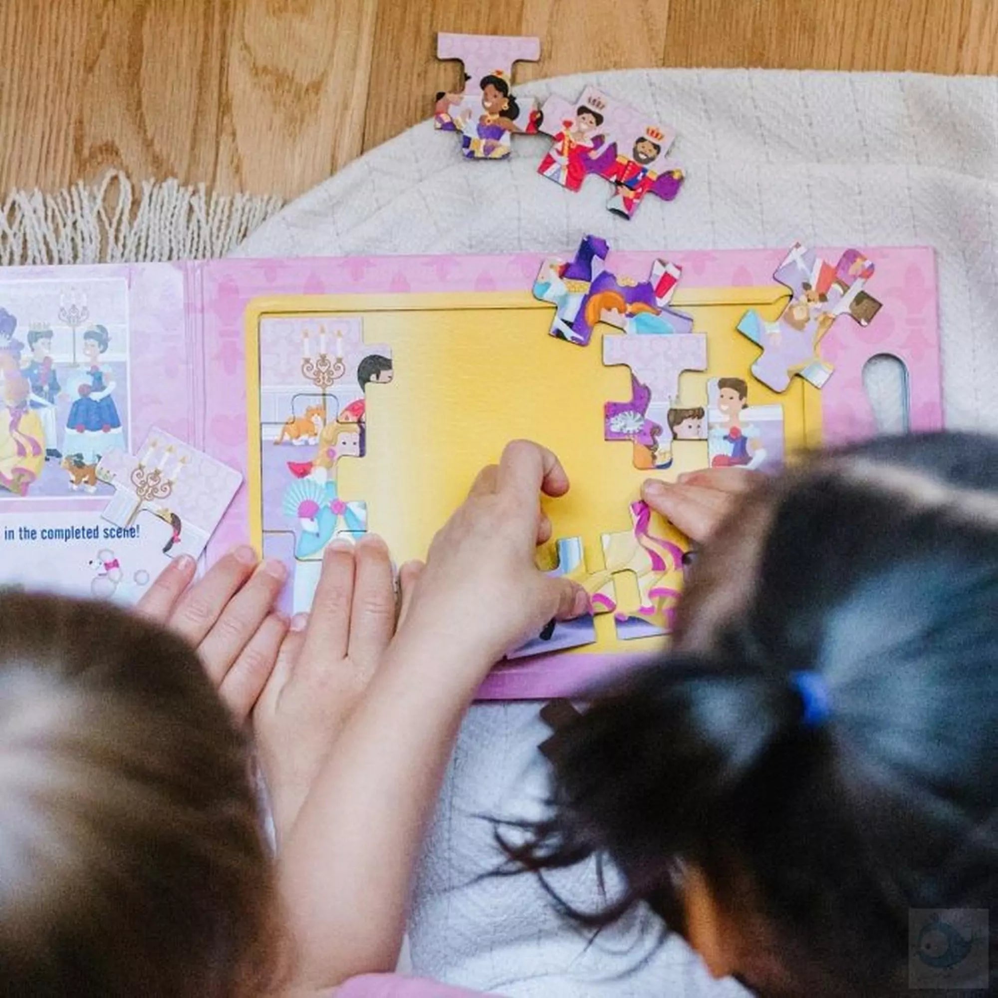 Gyerekek Melissa & Doug mágneses kirakó – Hercegnők darabjait illesztik össze a mágneses táblán, közelről látható a színes királyi bál jelenet.