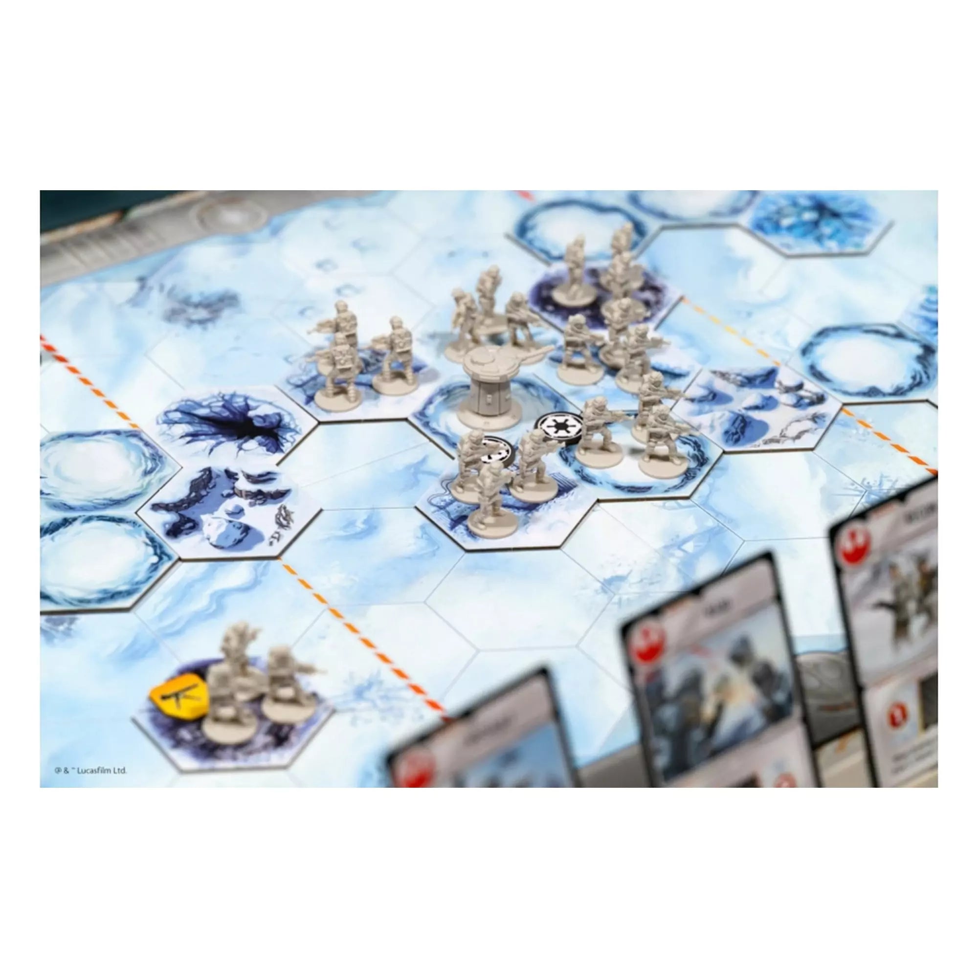 Közelkép a játéktábláról, ahol a lázadó katonák miniatűr figurái állnak, középen egy védelmi toronnyal.