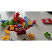 Tower Stack játék közben, színes piros, zöld, kék és sárga elemek egyensúlyoznak a piros alapra épített tornyon.