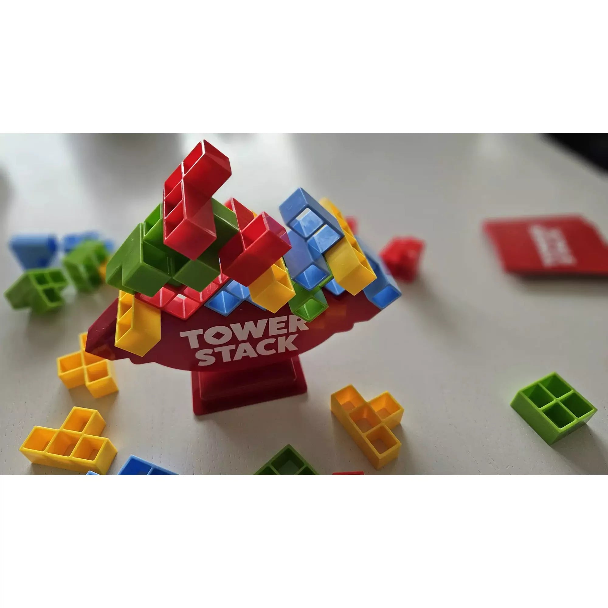 Tower Stack játék közben, színes piros, zöld, kék és sárga elemek egyensúlyoznak a piros alapra épített tornyon.