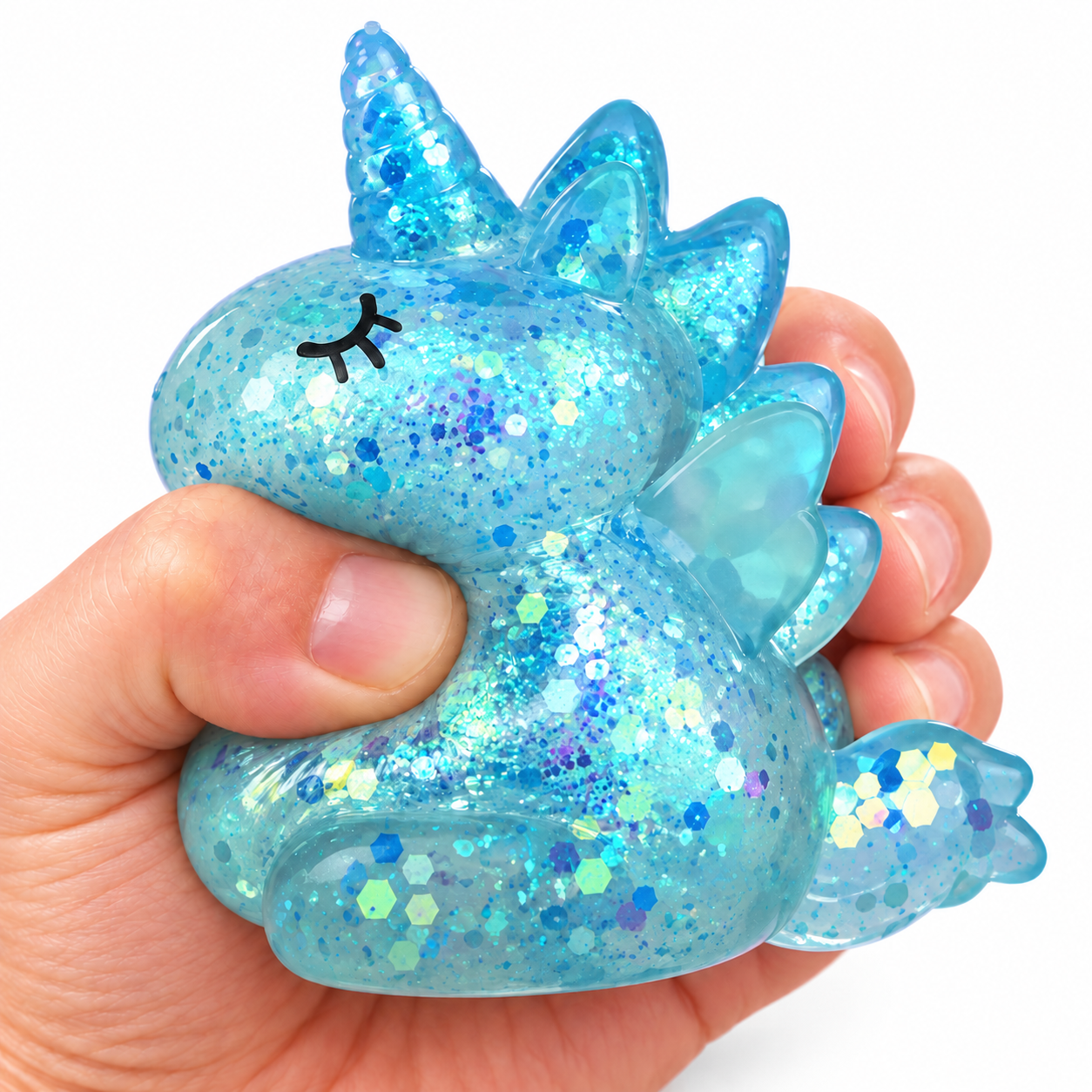 Kézben összenyomott kék, csillámos unikornis squishy stresszlevezető játék fehér háttér előtt