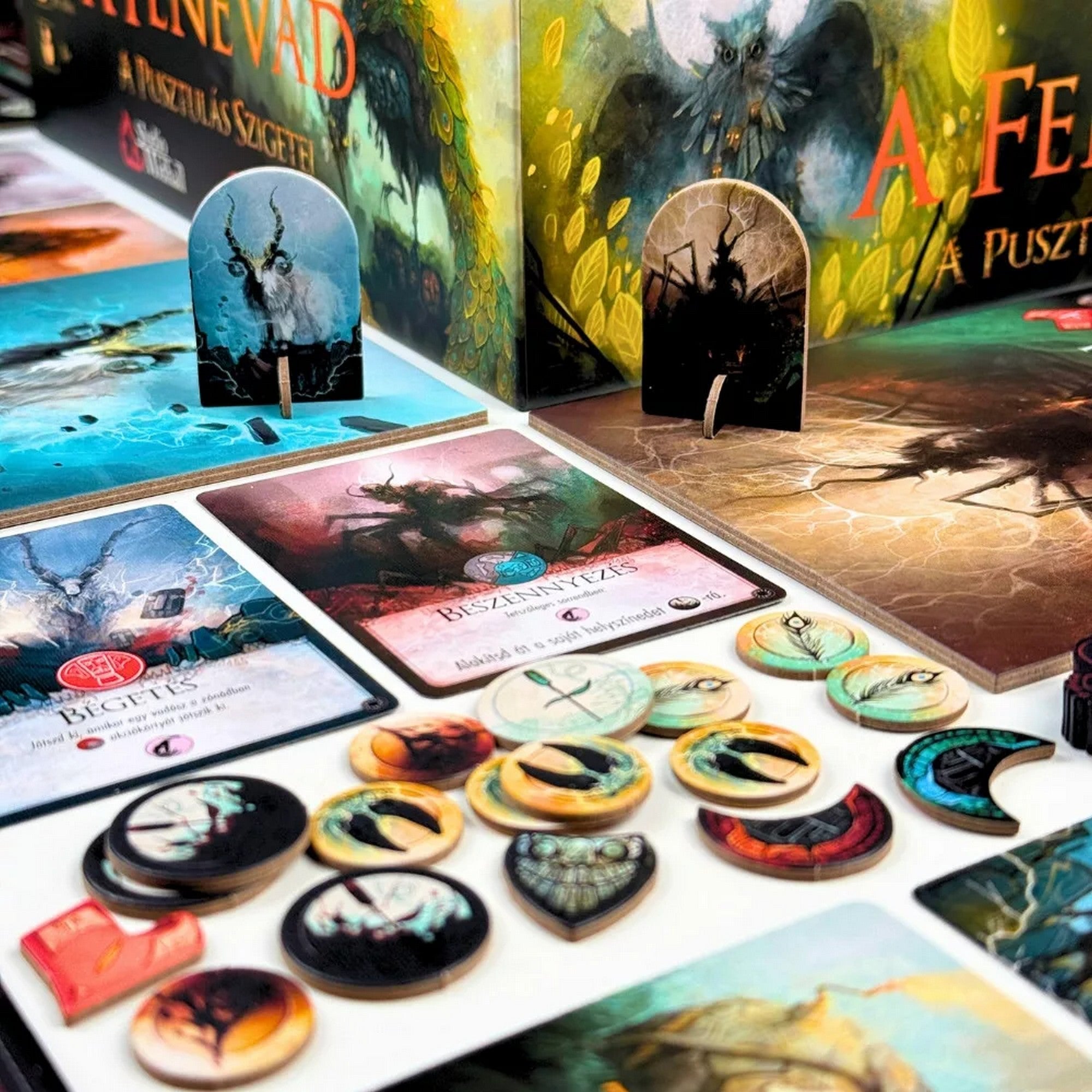 A Fenevad: A pusztulás szigetei társasjáték részletgazdag komponensei, kártyák, jelölők és karakterlapok közelről, fantasy hangulatú grafikákkal.