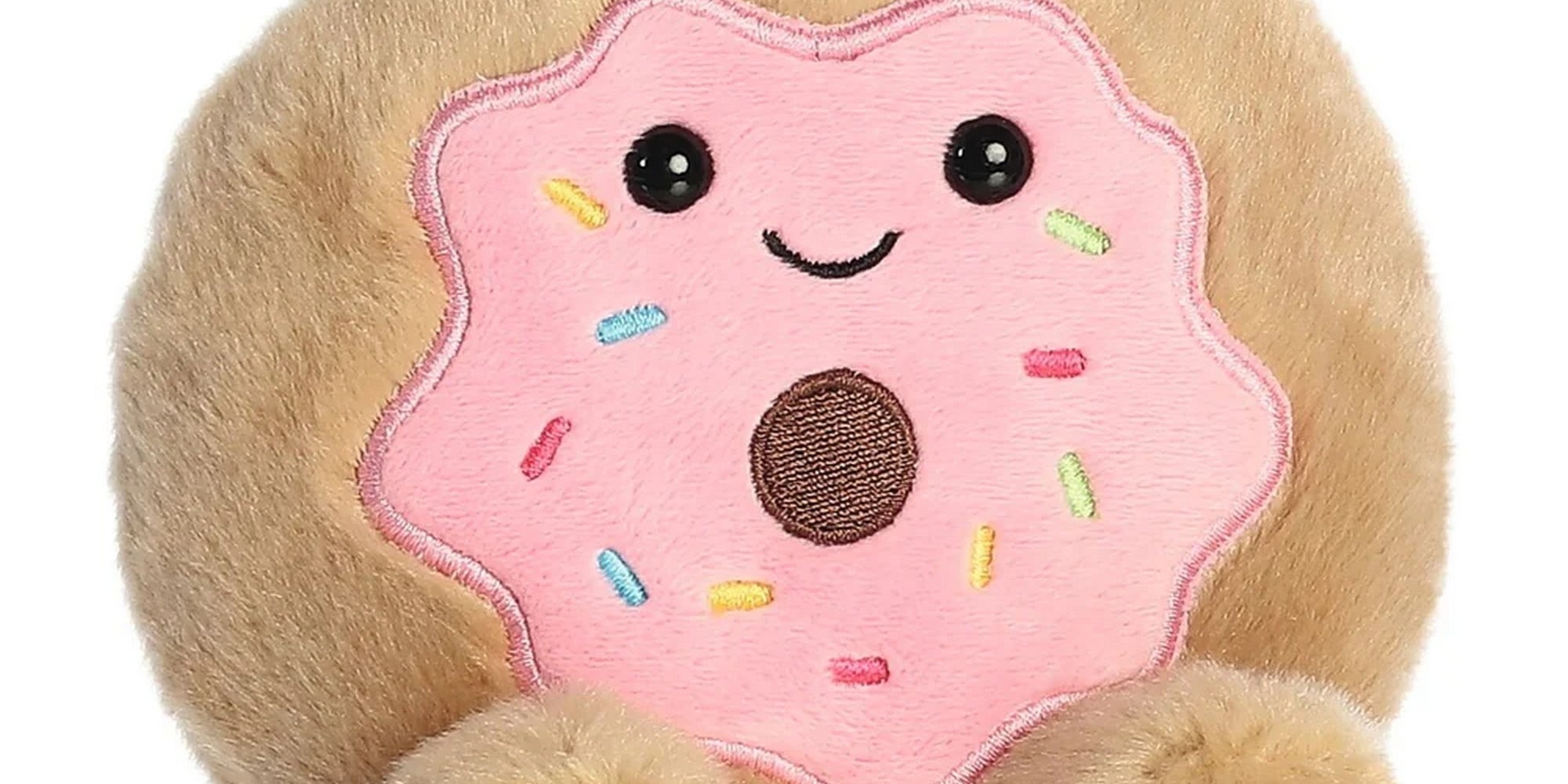 Fánk formájú plüss játék elölnézetben, rózsaszín mázzal, színes szórásokkal és mosolygós arccal, puha, selymes tapintású anyagból készült aranyos kialakítással
