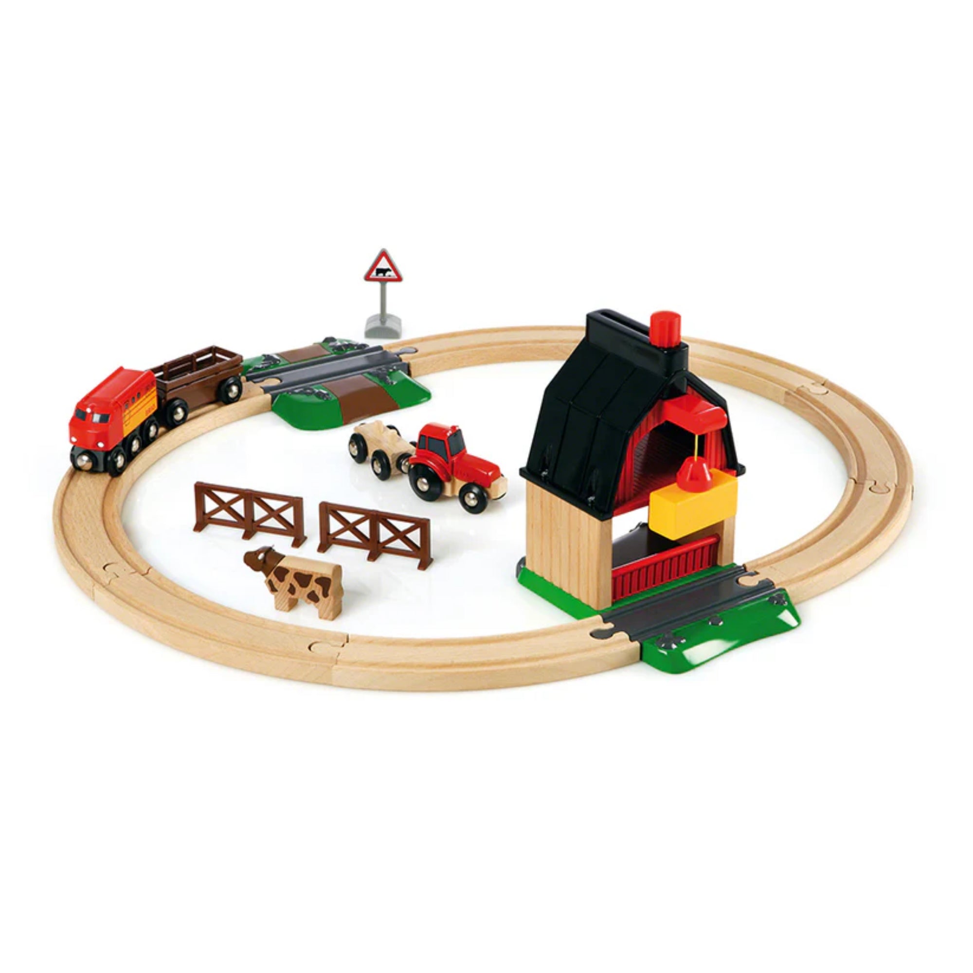 BRIO World Farm Railway Set teljes tartalma: kör alakú fa sínpálya, piros mozdony, traktor, pajta, tehén, kerítés és közlekedési tábla.