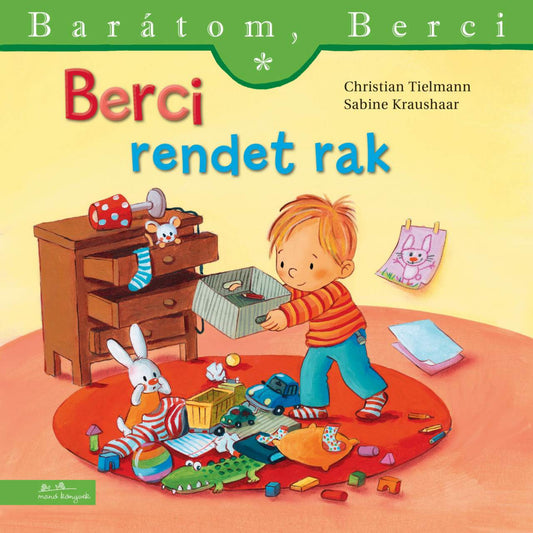 “Berci rendet rak” könyv borító – Berci a földre szétszórt játékokat pakolja látható dobozba, mögötte fiókos komód és a falon egy rajz.