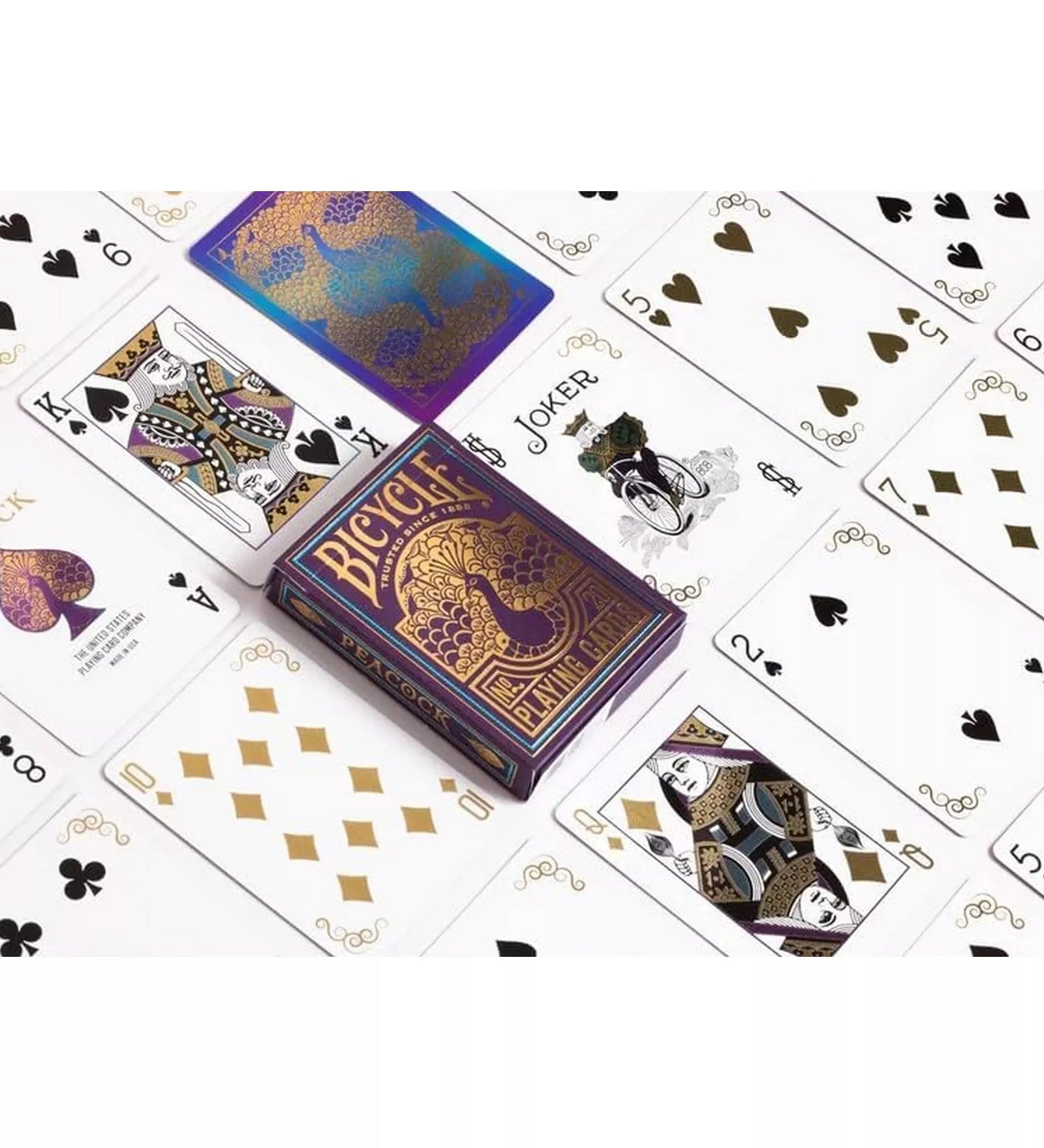 A Bicycle Peacock kártyapakli kiterítve, elegáns fekete, arany és fehér színekben, középen a doboz arany páva mintájával és klasszikus Bicycle lapokkal.
