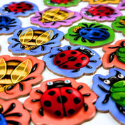 Bogártánc társasjáték fa rovarfigurái közelről, virág alakú lapkákon katicákkal és méhekkel.