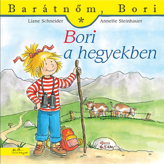 „Bori a hegyekben” borító – Bori túrázó ruhában, hátizsákkal és távcsővel egy hegyi ösvényen áll, háttérben tehenek, hegycsúcsok és egy 6,5 km-es tábla látható.