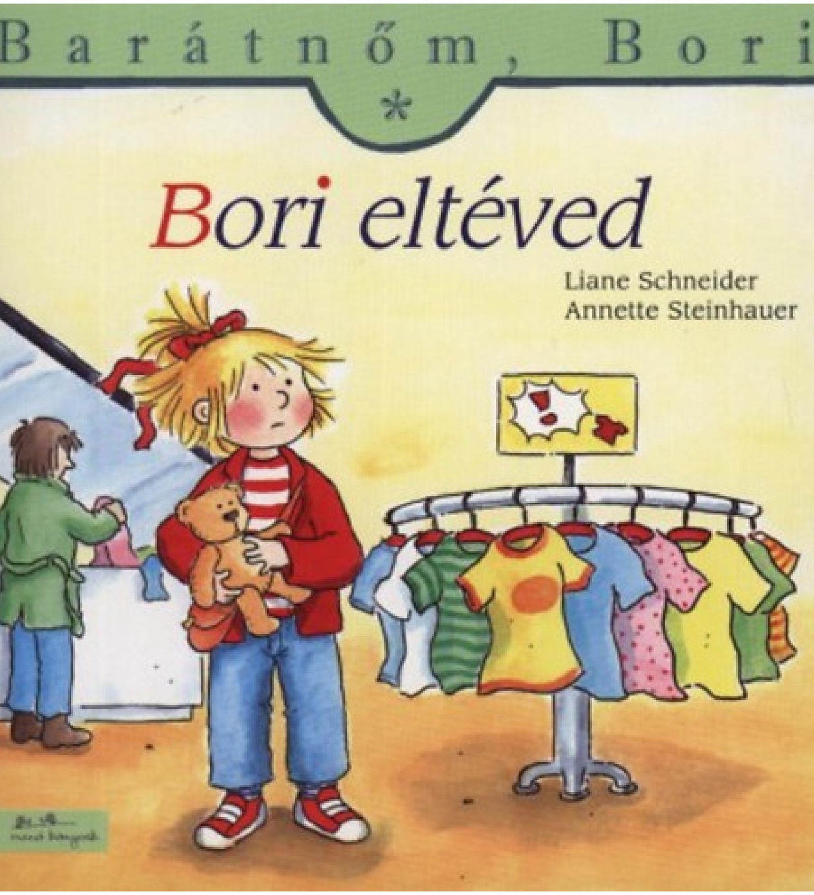 „Bori eltéved” borító – Bori egy ruhaboltban áll tanácstalanul, kezében a plüssmackóját szorongatja. A háttérben színes gyerekruhák lógnak egy kör alakú állványon, miközben Bori aggódva tekint körbe, keresve az ismerős arcokat.