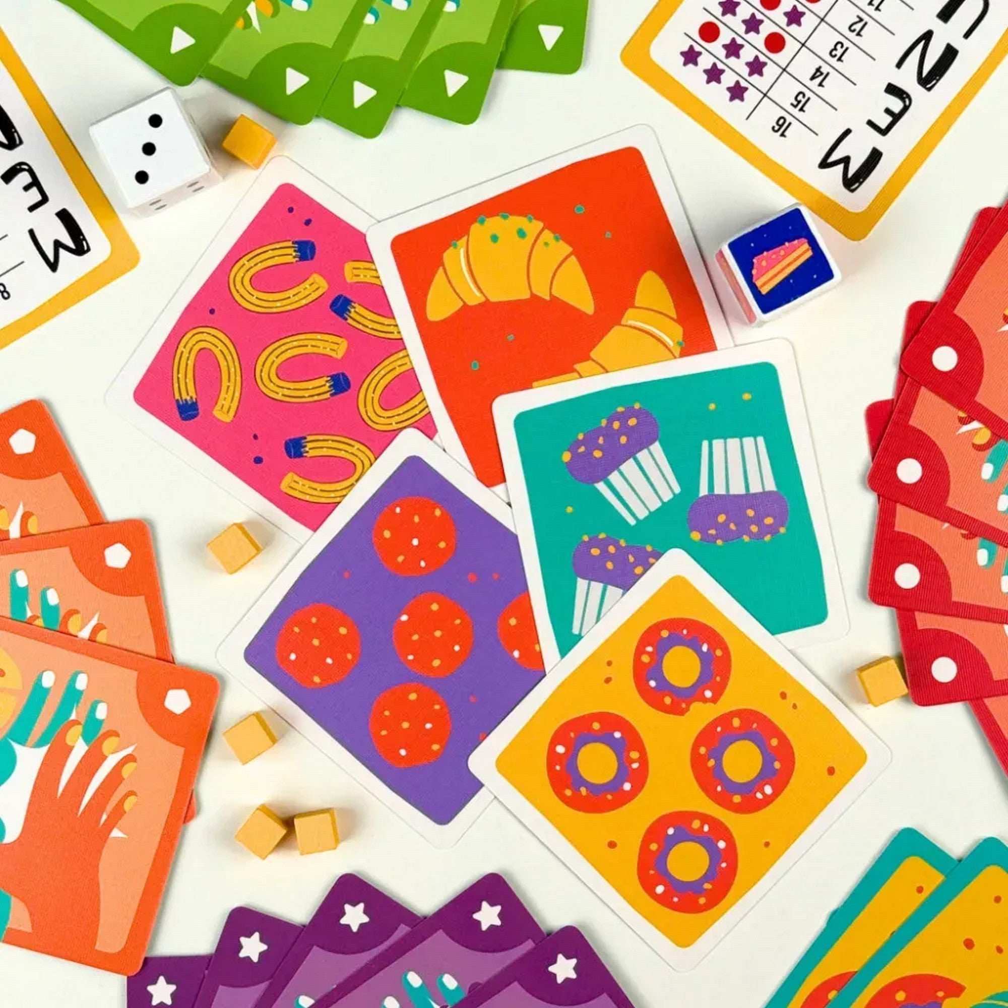 El a kekszekkel! – Színes játékkártyák édességmintákkal, kockákkal és jelölőkkel egy pörgős társasjátékhoz.