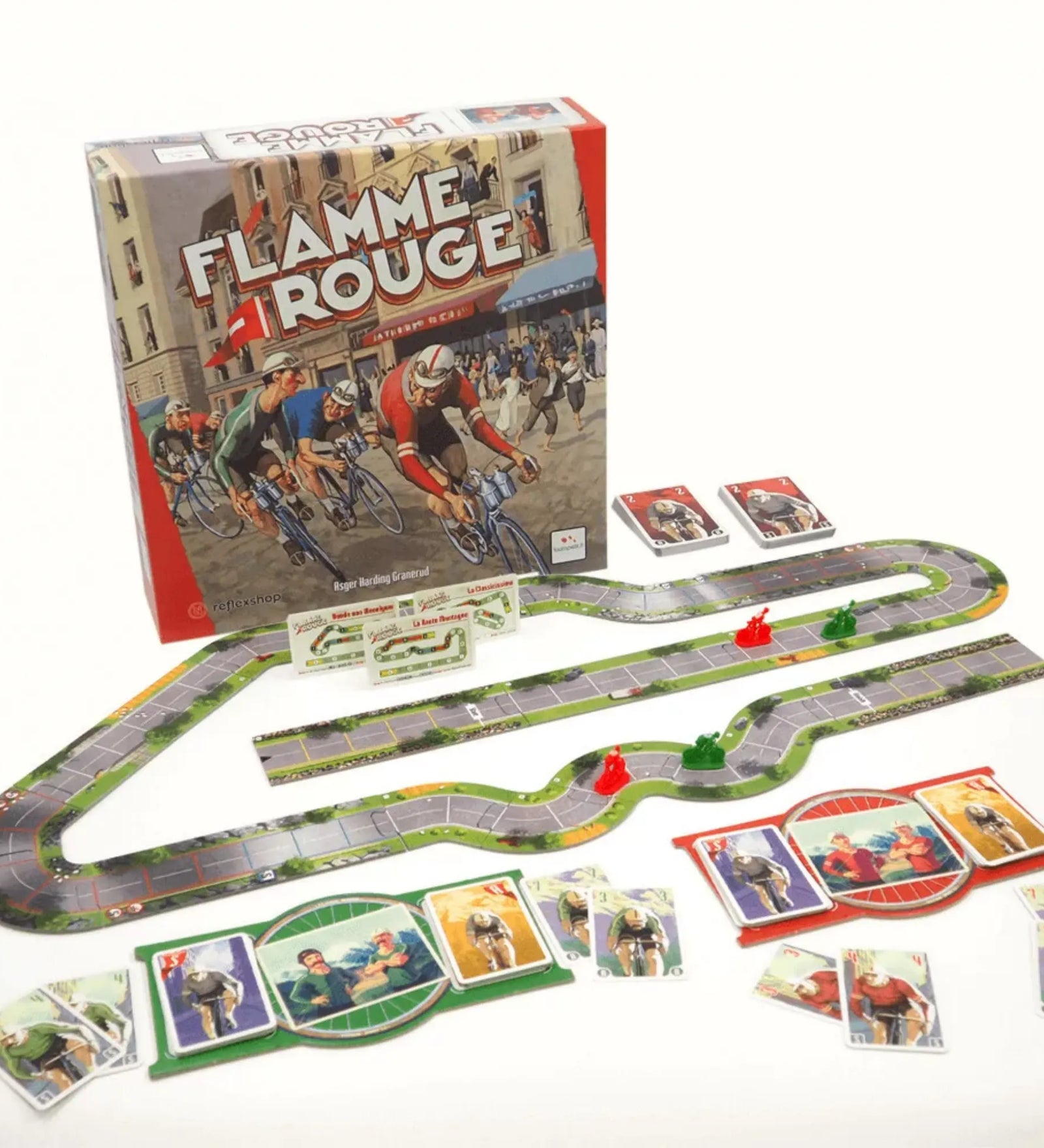 Flamme Rouge magyar nyelvű társasjáték doboza és teljes játékkészlete, moduláris versenypálya elemekkel, piros és zöld kerékpáros figurákkal, játékoskártyákkal és segédlapokkal egy asztalon elrendezve.