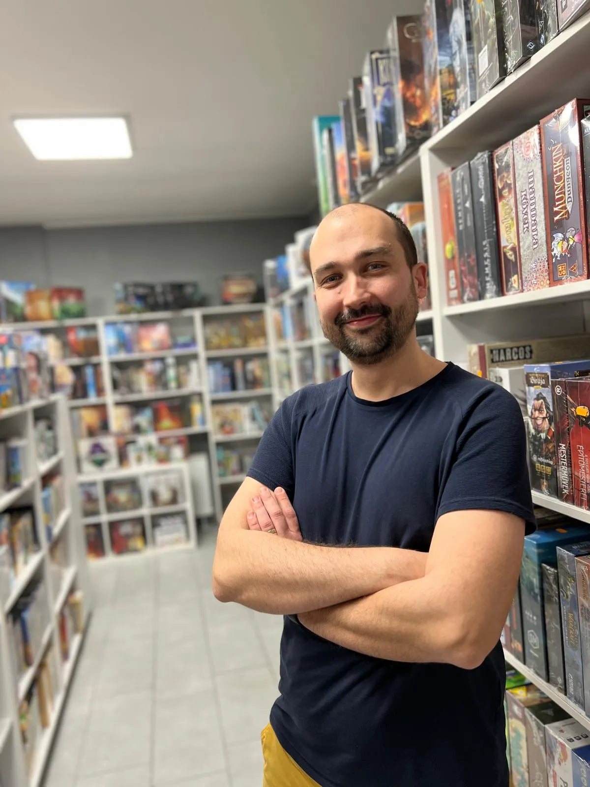 Játszma bolt alapitoja es SEO-ja társasjáték polcok előtt