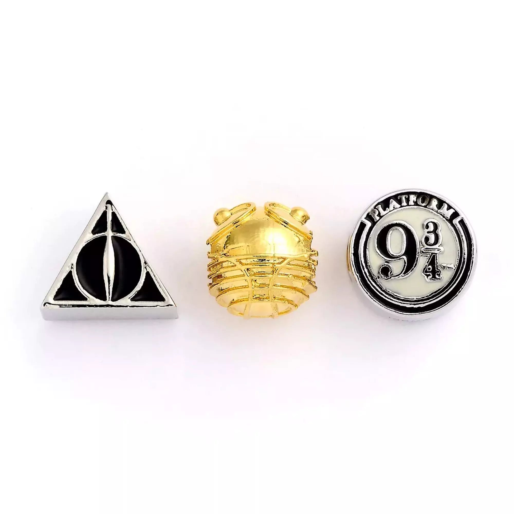 Három Harry Potter témájú gyöngy közelről: egy ezüst színű Halál ereklyéi szimbólum, egy aranycikesz formájú gyöngy és egy ezüst színű, 9 és 3/4 vágányt jelölő gyöngy.