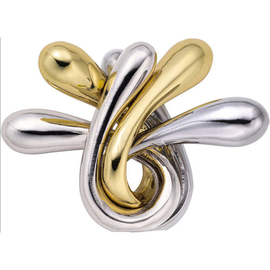 Fényes, összefonódott arany és ezüst színű fém elemekből álló, organikus formájú logikai játék, a Huzzle Cast RIPPLE, amelynek sima, csepp alakú végei elegánsan tekerednek egymásba.