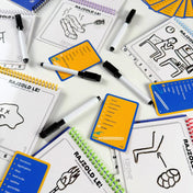 Képzavar társasjáték játékmenet közben, rajzfüzetekkel, filctollakkal és feladványkártyákkal, rajzos feladatokkal az asztalon.