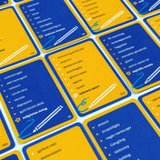 Képzavar társasjáték kártyák közelről, kék és sárga színű feladványlapokkal, rajzeszköz ikonokkal és különböző magyar szavakat tartalmazó listákkal.