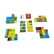 A Kingdomino társasjáték többjátékos elrendezésben – különböző birodalmak kialakítása, pontozólap és dominólapok a játék közepén.