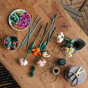 LEGO Flower Bouquet (10280) szett különböző virágdarabokkal egy fából készült asztalon szétszórva.