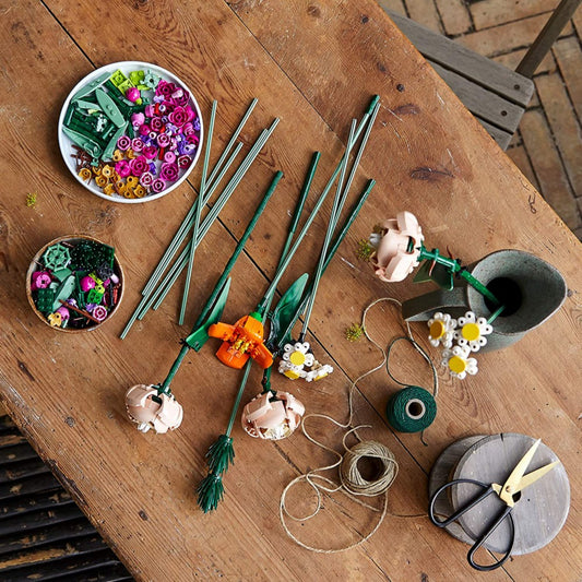 LEGO Flower Bouquet (10280) szett különböző virágdarabokkal egy fából készült asztalon szétszórva.