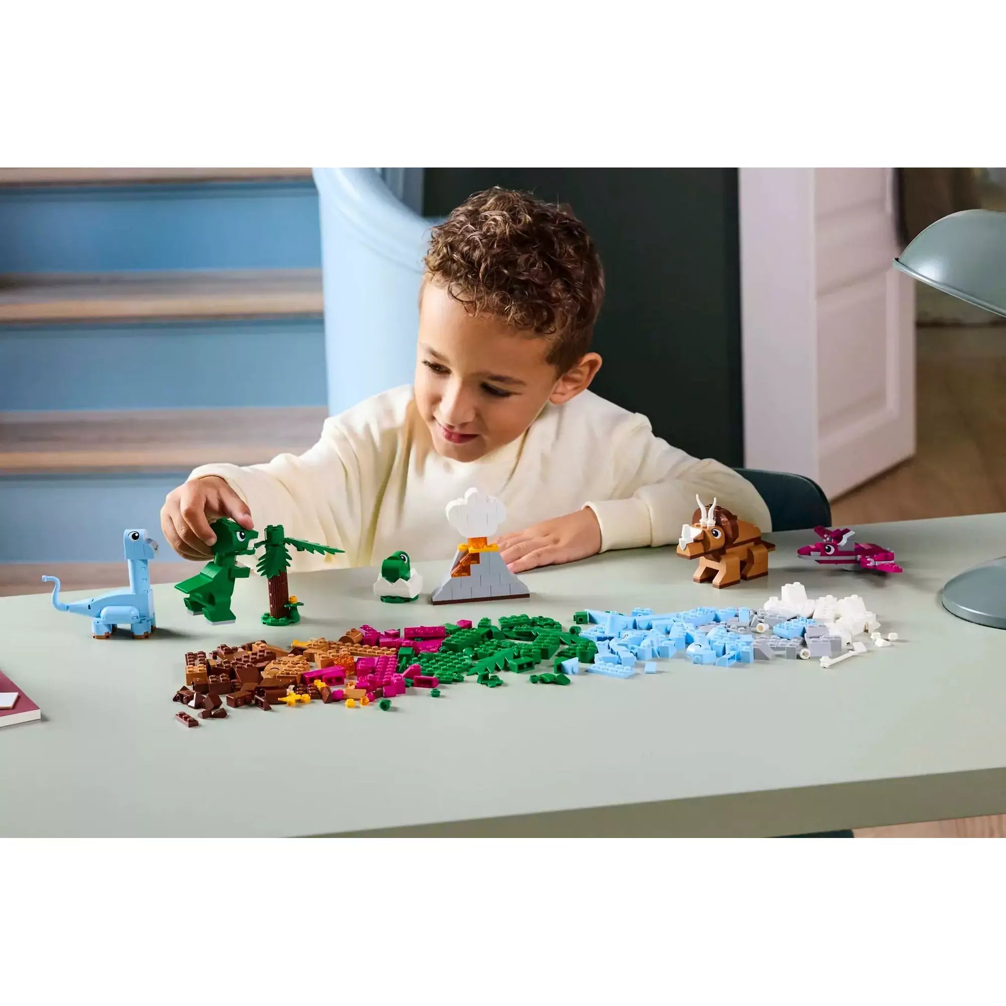 Egy gyermek játszik az "LEGO Classic Kreatív dinoszauruszok (11041)" készlettel, különböző dinoszauruszokat és kiegészítőket építve.
