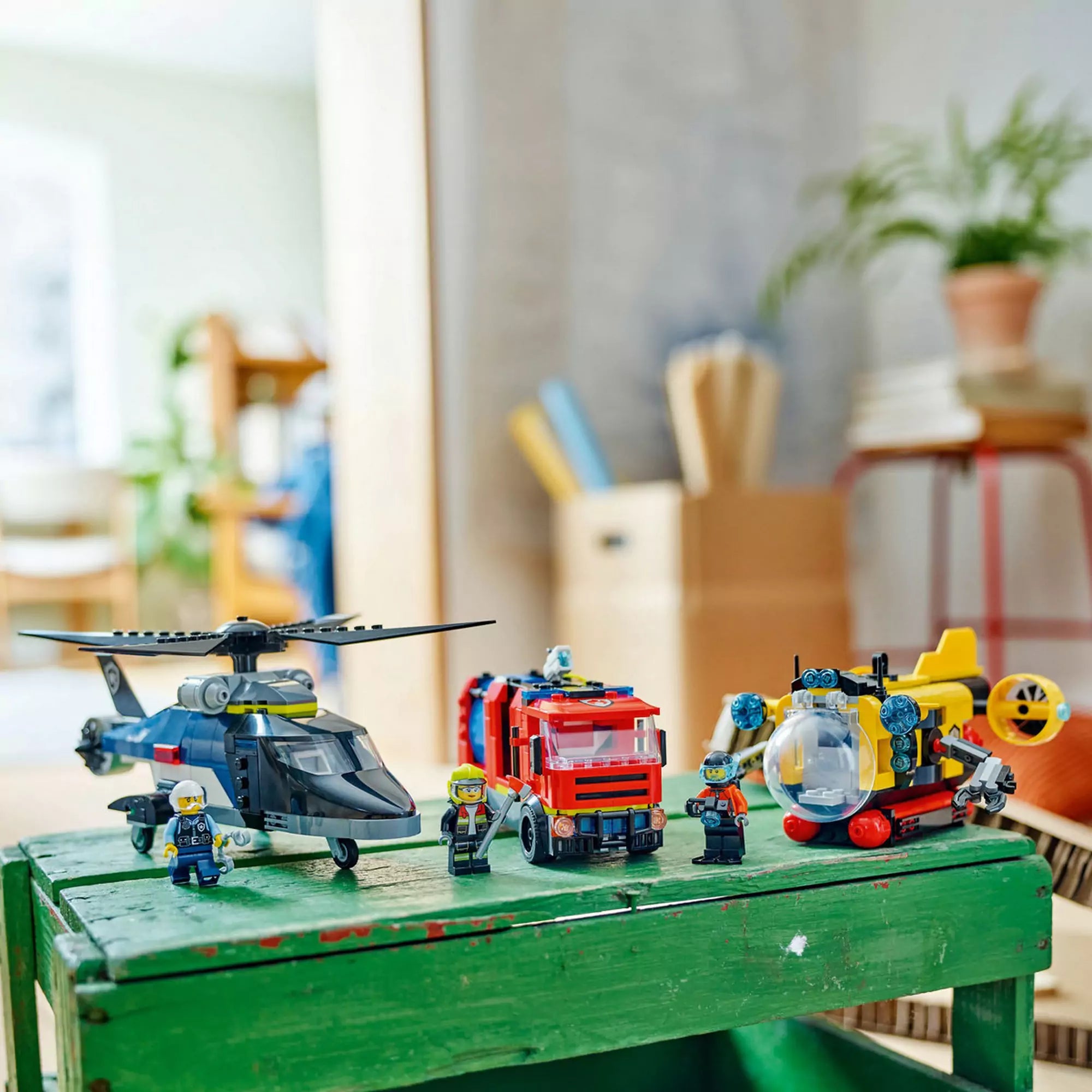 A LEGO City Helikopter, tűzoltóautó és tengeralattjáró modellek minifigurákkal a háttérben.
