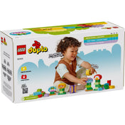 A LEGO DUPLO Kreatív kert és virágok (10444) hátoldala, amely megmutatja a játék építési lehetőségeit, és egy boldog kisgyermek látható, aki a szettet használja

