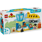 A LEGO DUPLO 10443 Első repülés a repülőtéren színes doboza, előtérben a sárga repülőgép, az irányítótorony, a pilóta, a kisgyerek figura, a bőrönd és a kiegészítők láthatók; bal alsó sarokban a 2+ korosztály jelölés és a 23 darabos készletinformáció.