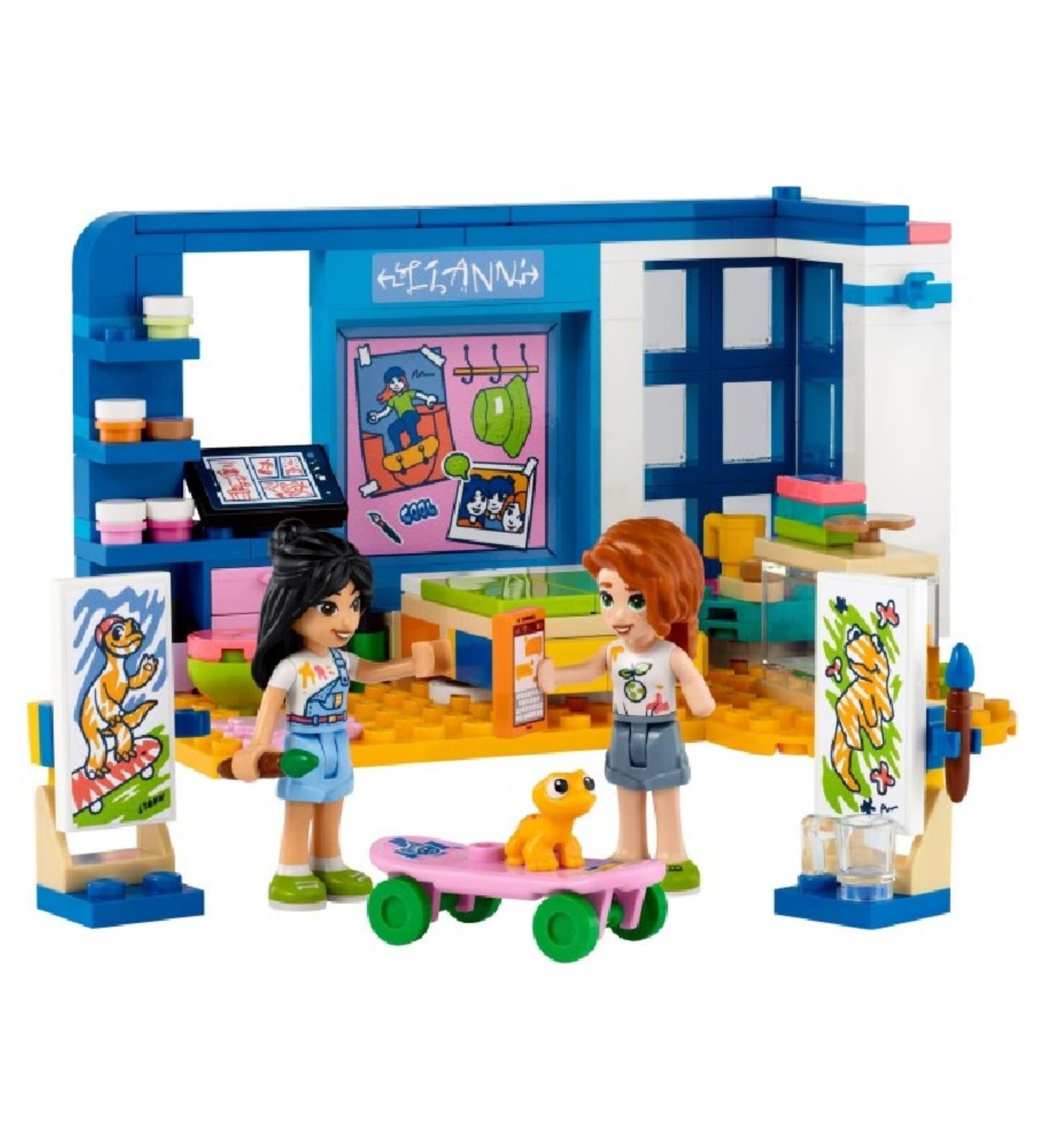 LEGO Friends 41739 Liann szobája – a teljes játékkészlet szemből: két minifigura (Liann és Autumn), festőállványok, ecsetek, egy terrárium sárga gyíkkal, színes bútorok és poszterek, valamint egy pink gördeszka zöld kerekekkel. A jelenet egy kreatív, művészi szobabelsőt ábrázol.