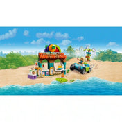 LEGO Friends Smoothie stand a strandon készlet tengerparti jelenetben. A gyümölcsdíszes smoothie bár, a strandjáró jármű, Nova és Niko figurák, egy szörfdeszka és egy teknősfigura látható a vízparton.