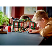 Két gyermek játssza el a LEGO Harry Potter Mágiaügyi Minisztérium (76403) jeleneteit az asztalon elhelyezett készlettel és minifigurákkal.