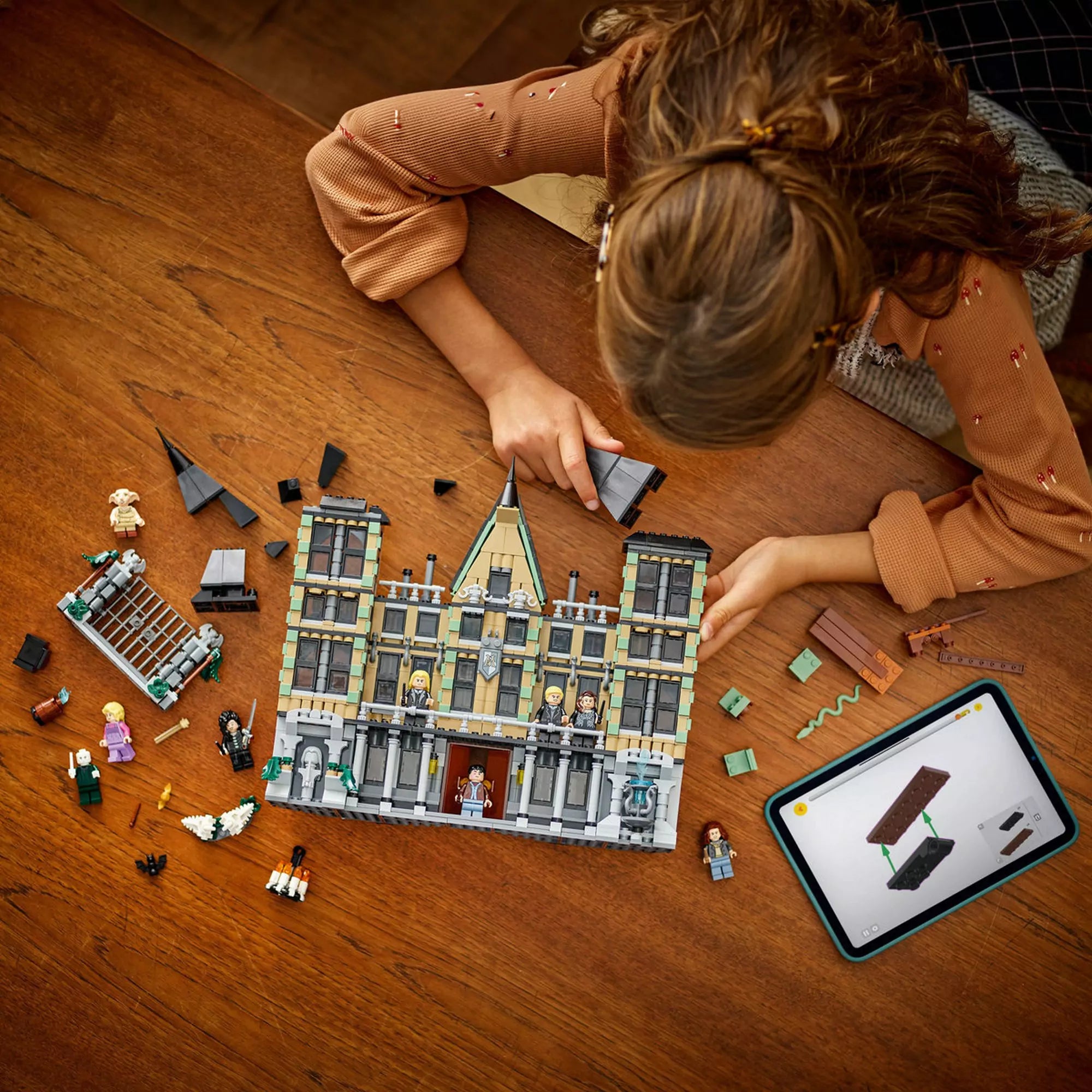 LEGO Harry Potter Malfoy-kuria építése (76453) – egy gyermek összerakja a részletes kastélyt, miközben a LEGO Builder alkalmazást használja.