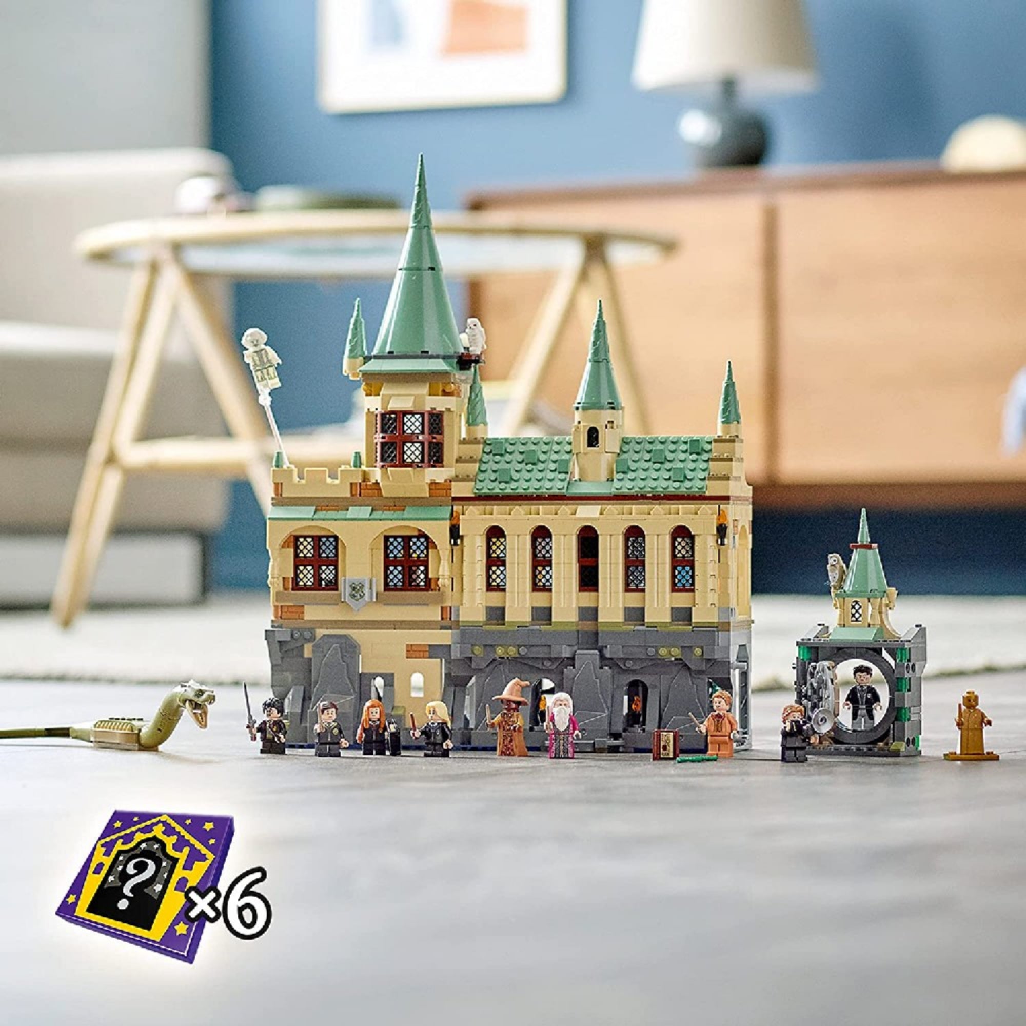 LEGO Harry Potter Roxfort Titkok Kamrája 76389 – összeszerelt kastély modern nappaliban kiállítva, előtte a 10 minifigura és a Baziliszkusz, 6 varázslókártyával.